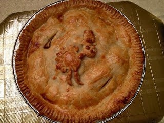 A pizza sitting on top of a metal pan, with Apple and Pie