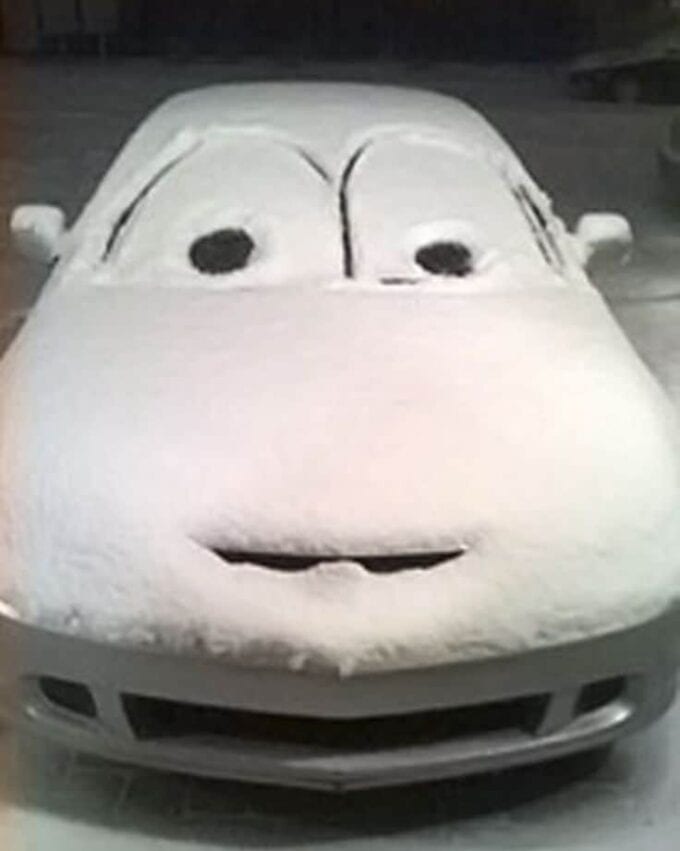 A close up of a car with a face made out of the snow