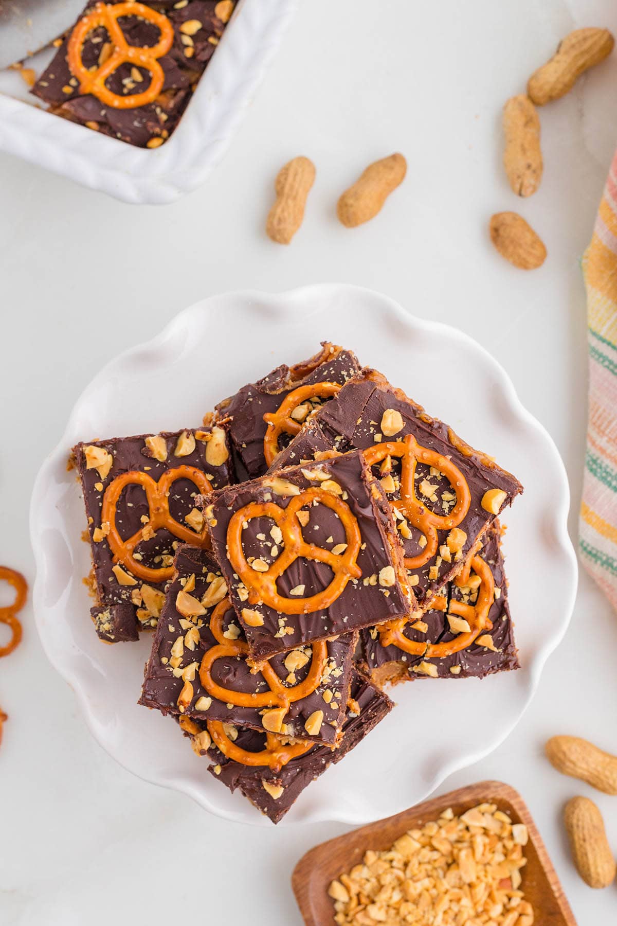 a couple of chocolate peanut butter pretzel bars with crushed peanuts.