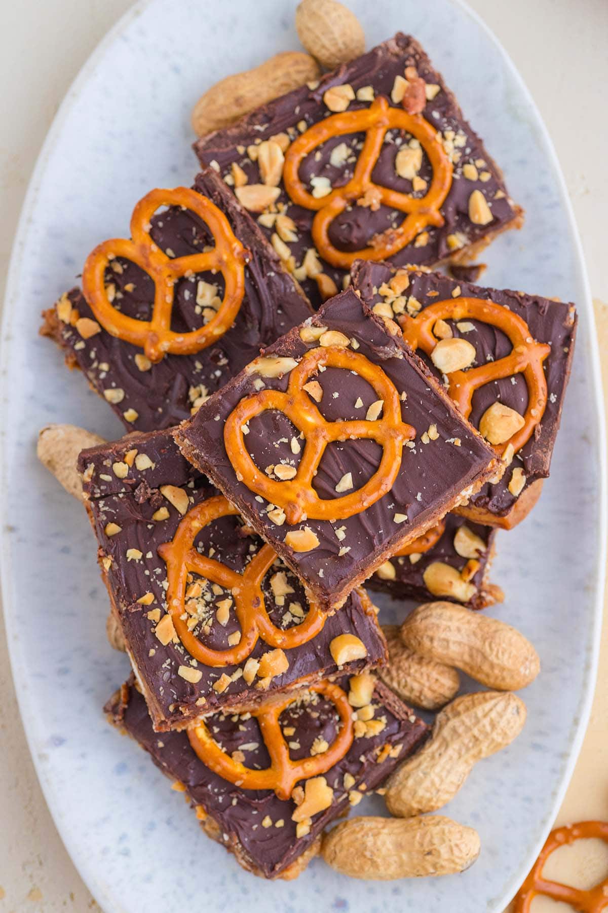 a couple of chocolate peanut butter pretzel bars topped with pretzel and crushed peanuts.