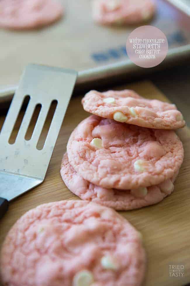 White chocolate strawberry cookies on a wood board with a spatula