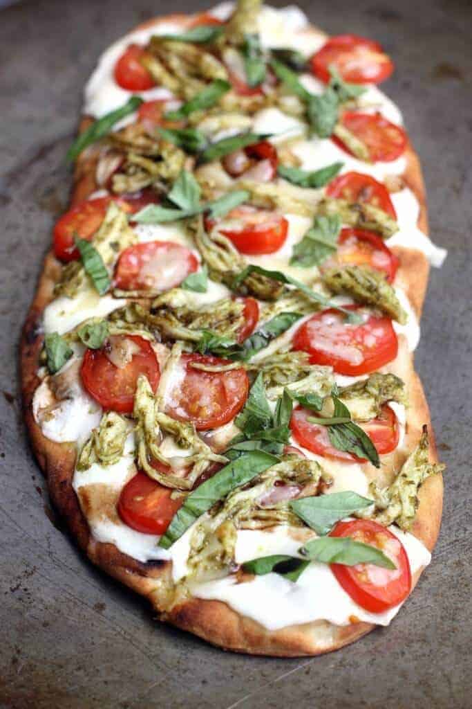 A pizza sitting on top of a wooden cutting board, with Chicken and Flatbread