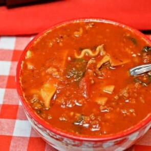 A bowl of lasagna soup with a red background