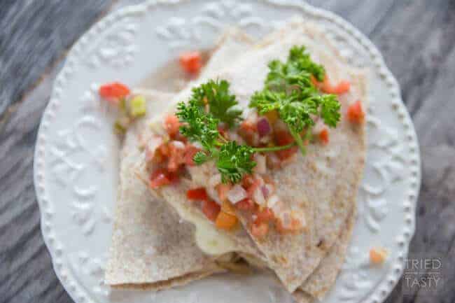 A slice of pizza on a paper plate, with Tortilla and Quesadilla