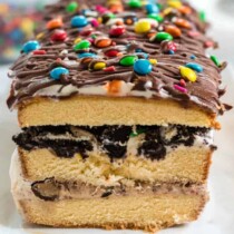 A close up of a piece of ice cream cake with chocolate on top and M&Ms