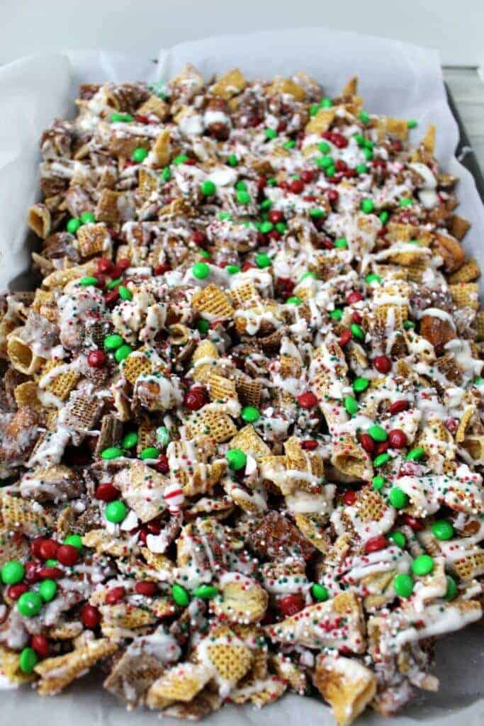 Chex mix with white chocolate and Christmas colored sprinkles and red and green M&Ms in a baking pan