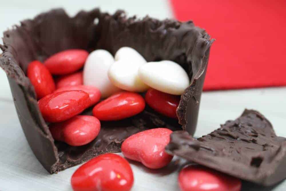 A close-up of a chocolate Harpal cracked open with heart candies falling out of it