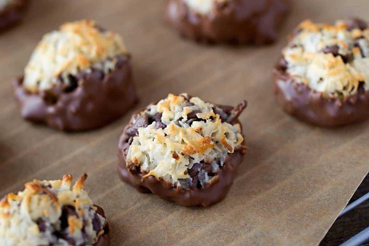 Chocolate-dipped chocolate chip macaroons on parchment paper.