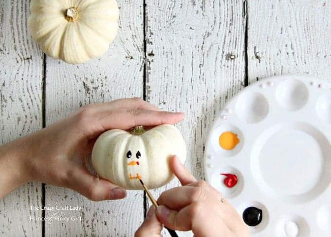 Paint the face on the pumpkin for this mini turkey pumpkin craft for Thanksgiving