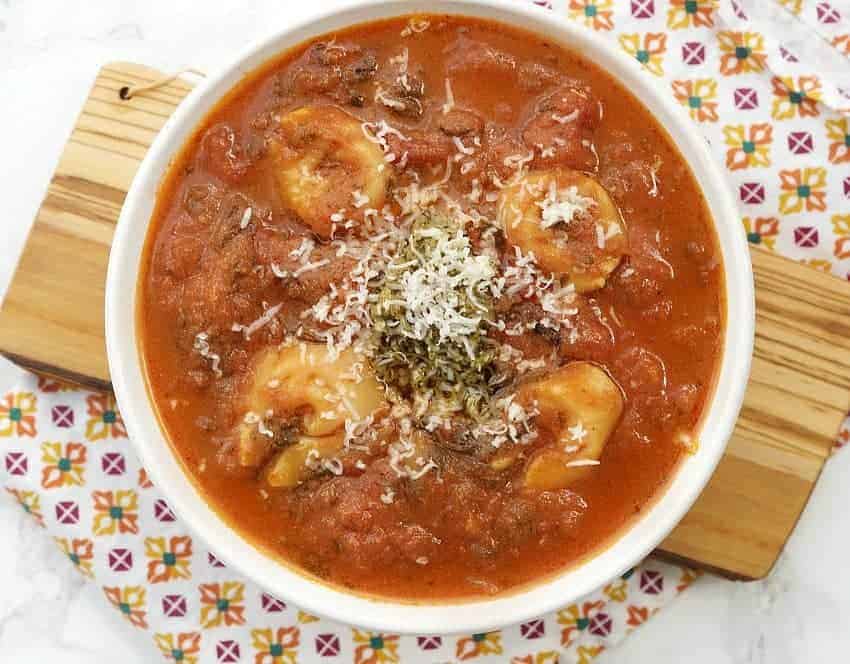 A bowl of soup, with Tomato and Tortellini