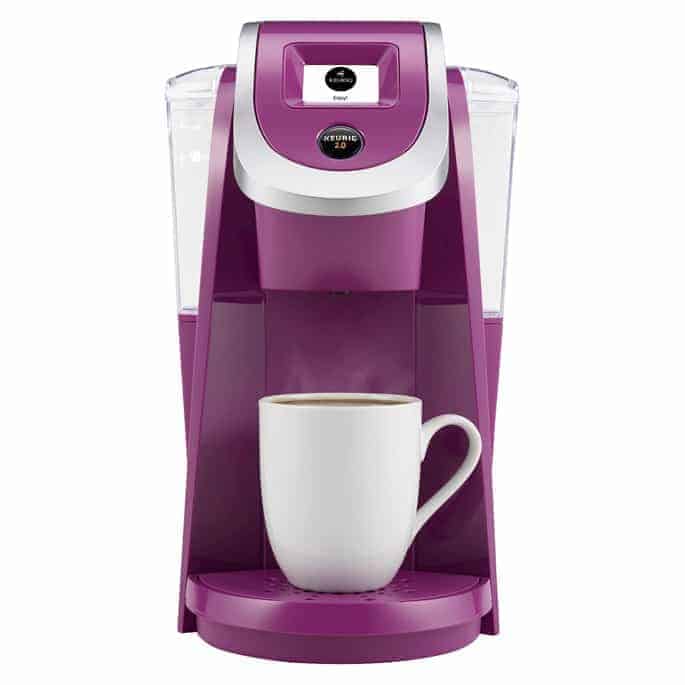 A purple coffee maker with a coffee cup