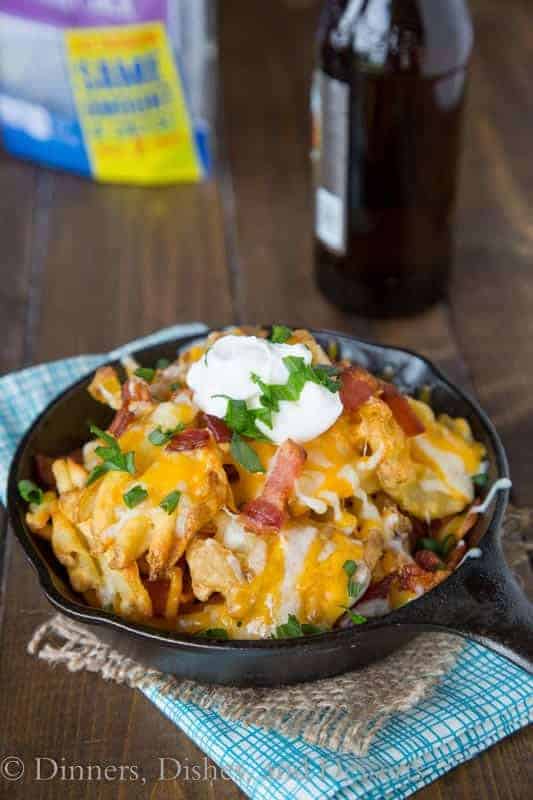 Nachos with cheese bacon sour cream and onions in a black bowl on the table
