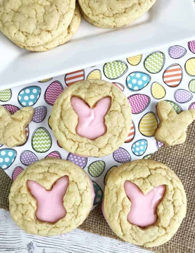 Sugar cookies with a cut out of the Easter bunny\'s silhouette filled with pink frosting on an Easter egg background