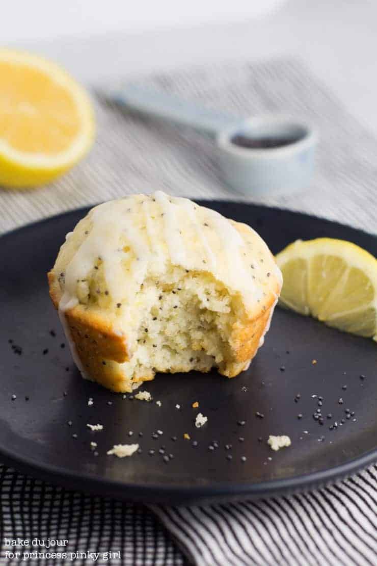 A lemon poppyseed muffin on a plate with a bite out of it