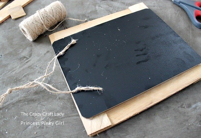 A piece of string being glued onto a chalkboard