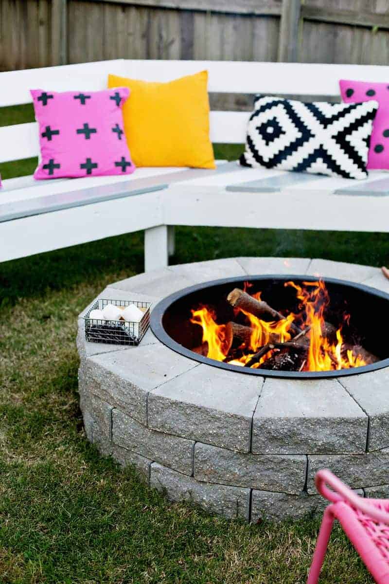 A fire pit with marshmallows next to it and a bench behind it