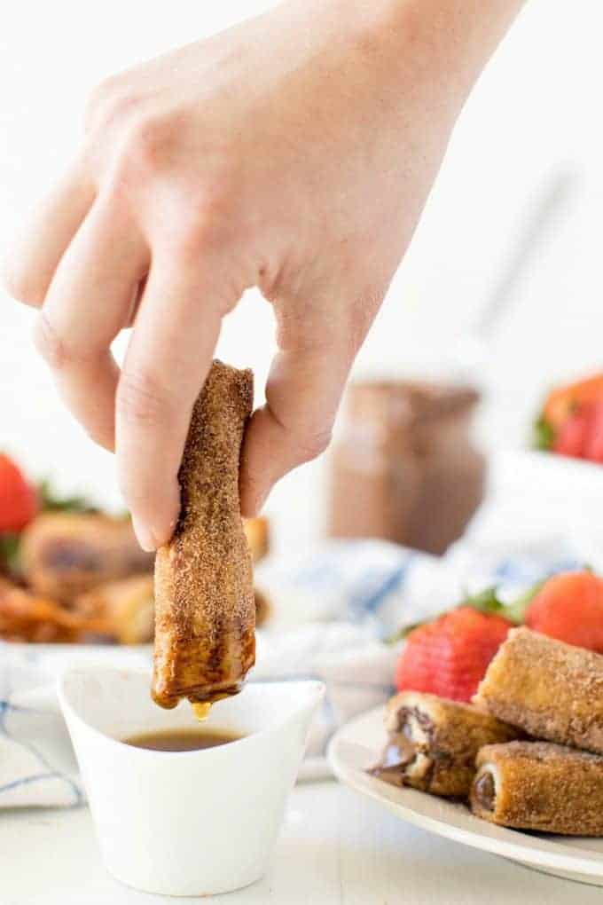 Nutella French Toast Roll Ups dipping into syrup