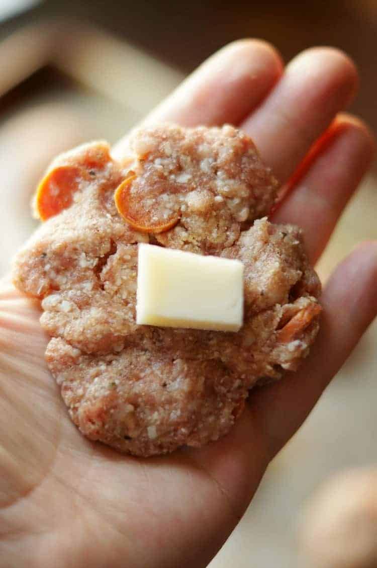 Close up of a raw meatball with a piece of cheese in it