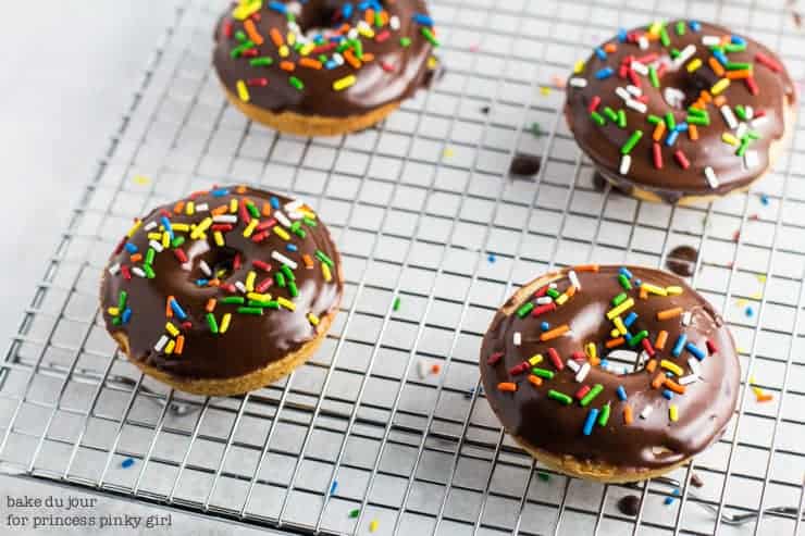 A set of 4 Chocolate Frosted Doughnuts on a wire rack