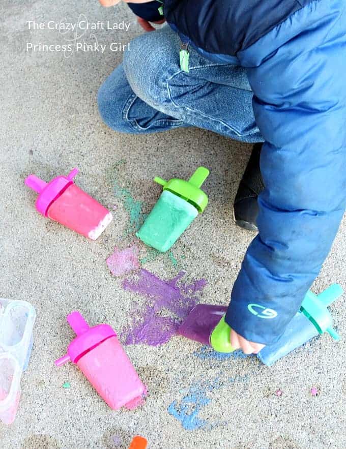 A child playing with popsicle sidewalk chalk outside