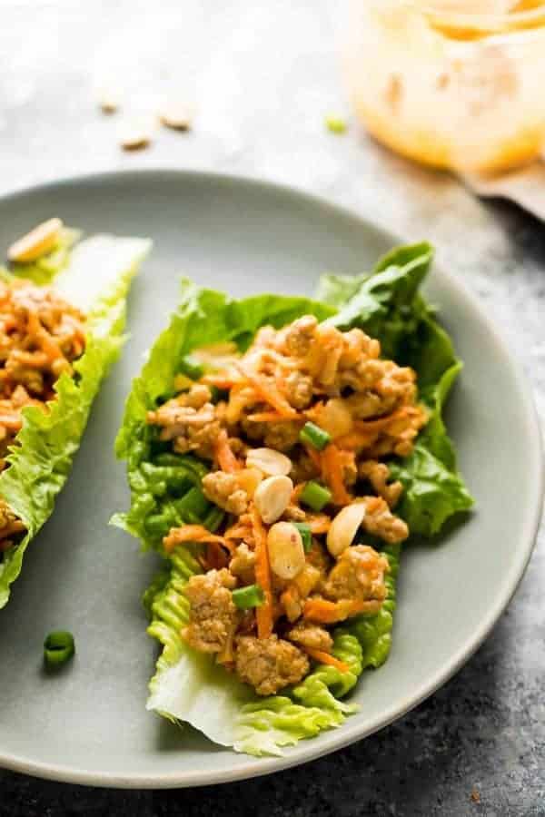 A chicken lettuce wrap on a white plate