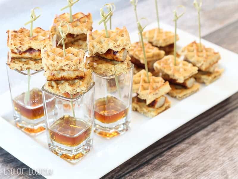 Bite-size chicken and waffles with syrup on a white plate