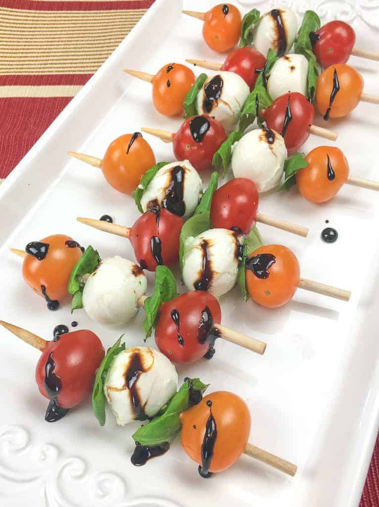 Caprice salad skewers with a balsamic glaze on a white plate