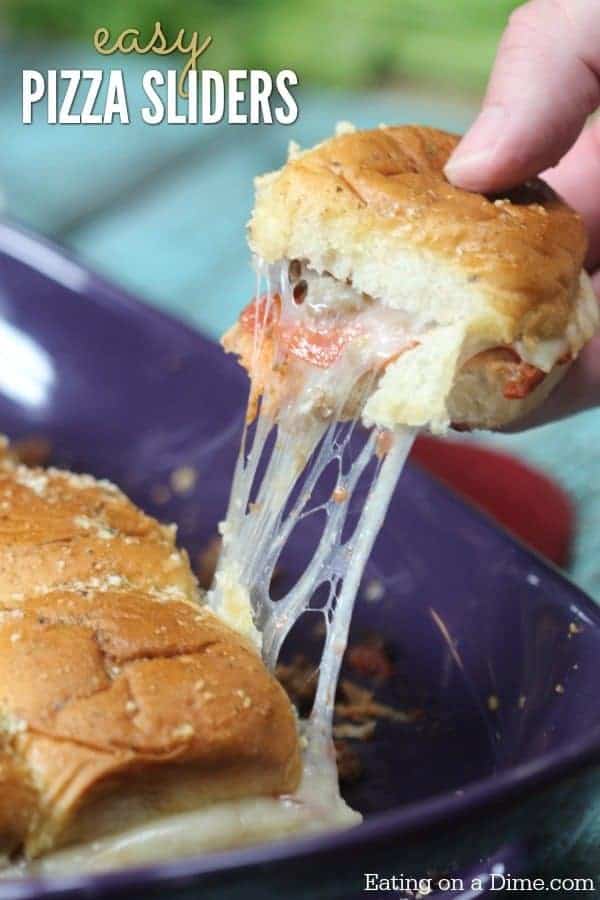 Pizza sliders being pulled out of a casserole dish