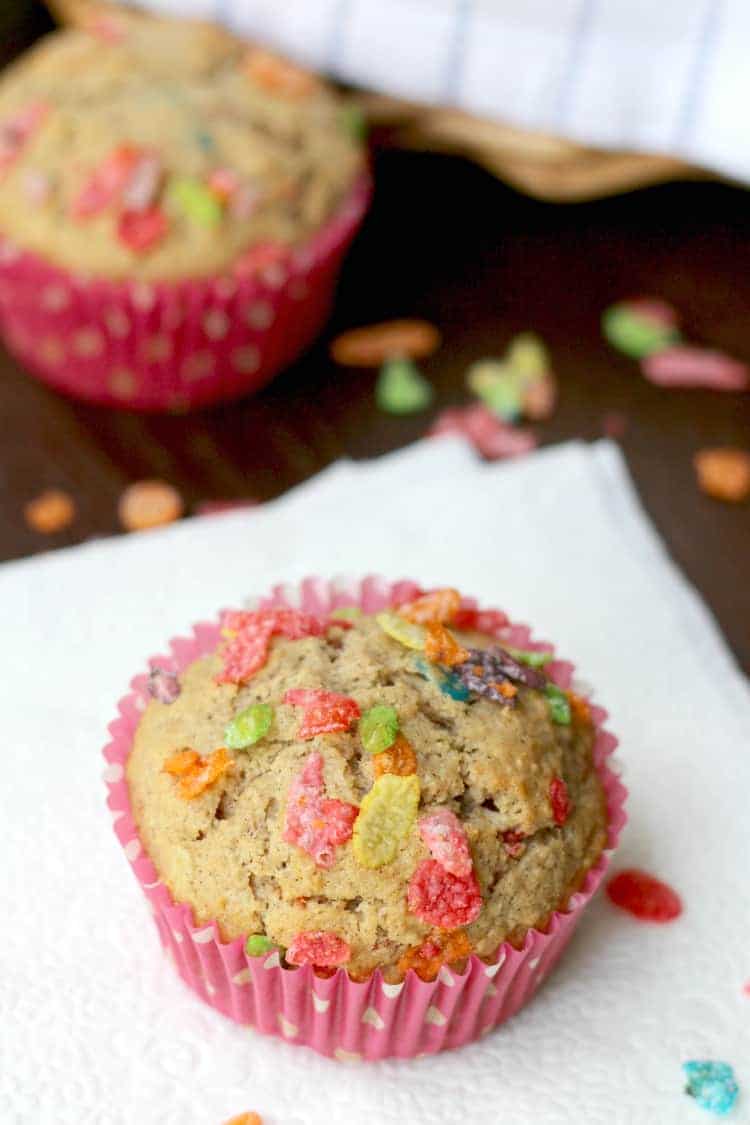 A muffin with fruity pebbles on top and a white napkin