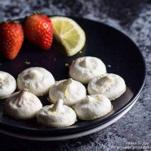 Lemon meringue cookies and a black plate with strawberries and a lime in the background