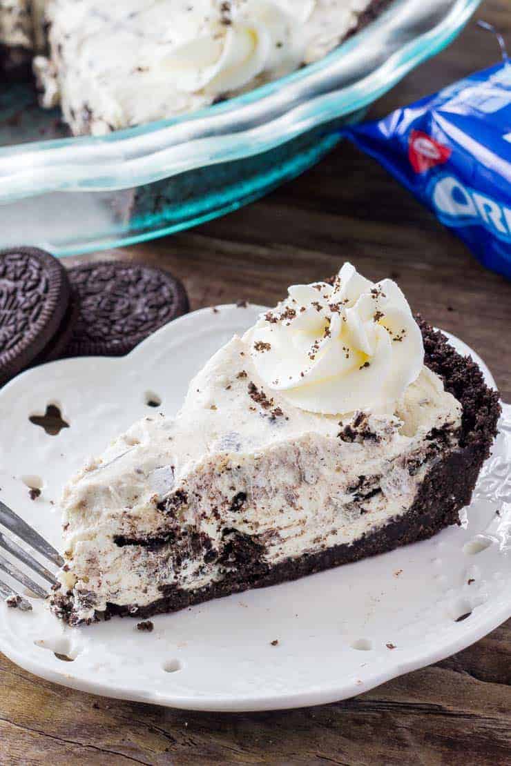 A slice of Oreo cream pie and a white plate with Oreos in the background