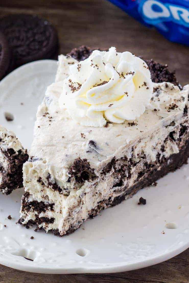 A piece of Oreo cream pie with a bite taken out of it on a white plate