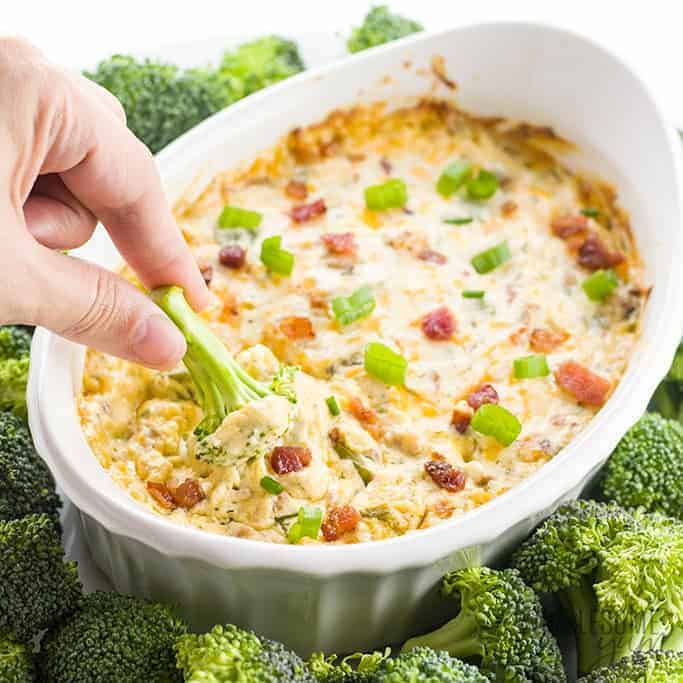 Ranch crack dip in a bowl with broccoli being dipped in it