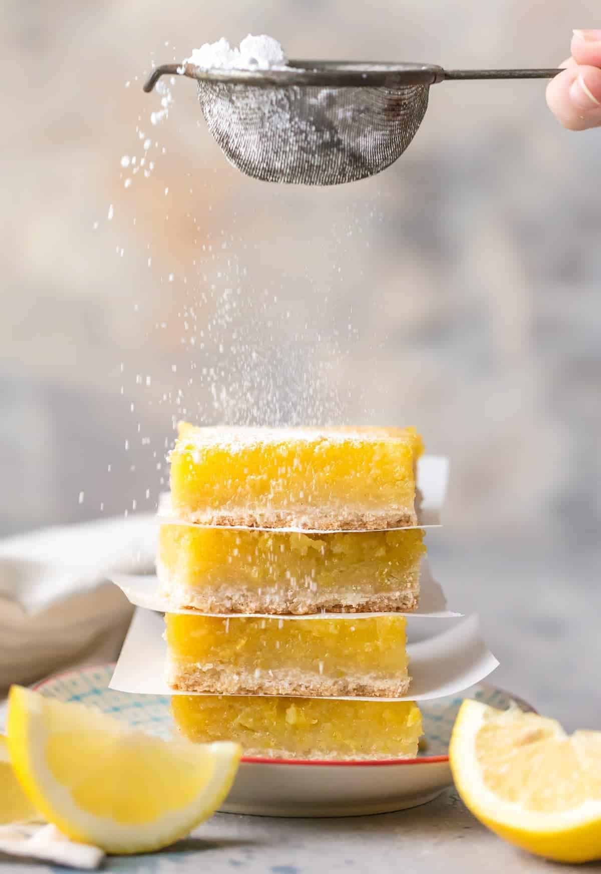 Lemon bars being sprinkled with powdered sugar