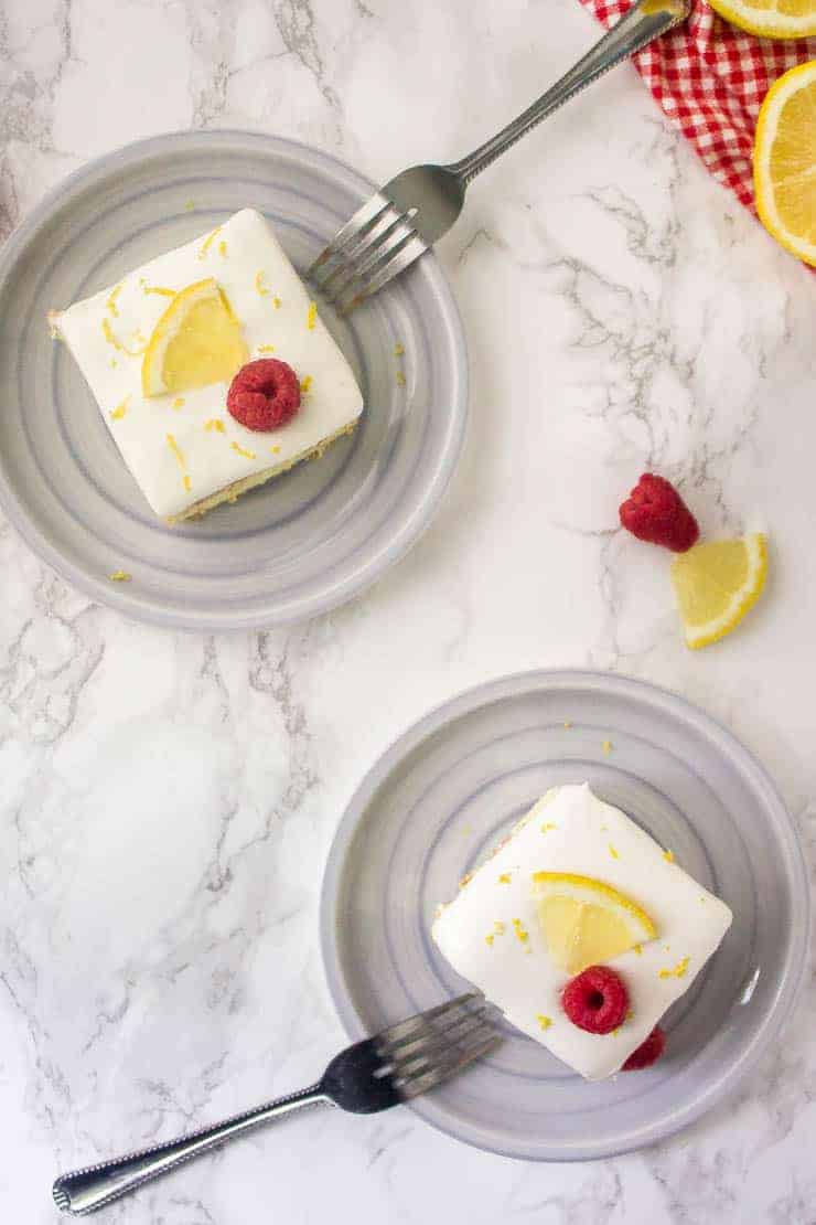 Lemon icebox cake on grey plates with raspberries and lemon