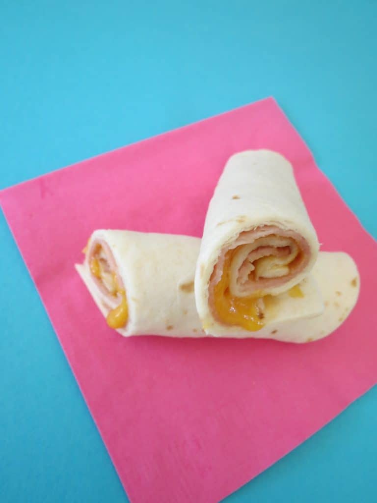 Ham and cheese roll up on a pink napkin