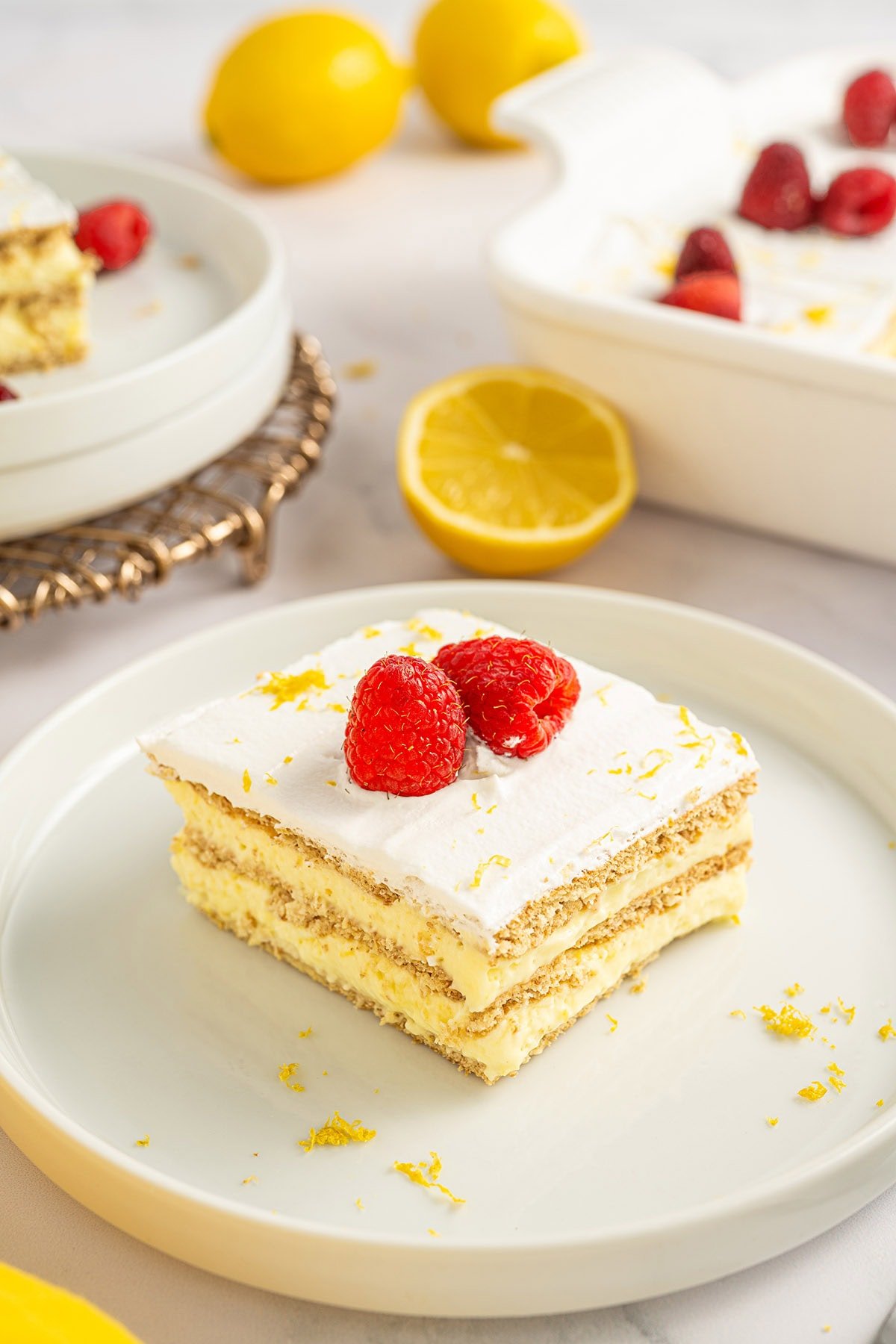 Lemon icebox cake slice topped with whipped cream and fresh raspberries.