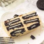 A slice of peanut butter Oreo ice box cake on a white plate with a fork