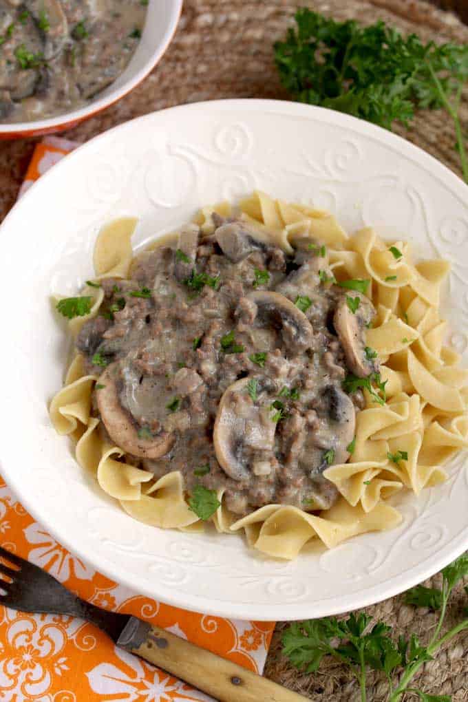 A bowl of food on a plate, with Beef and Beef Stroganoff