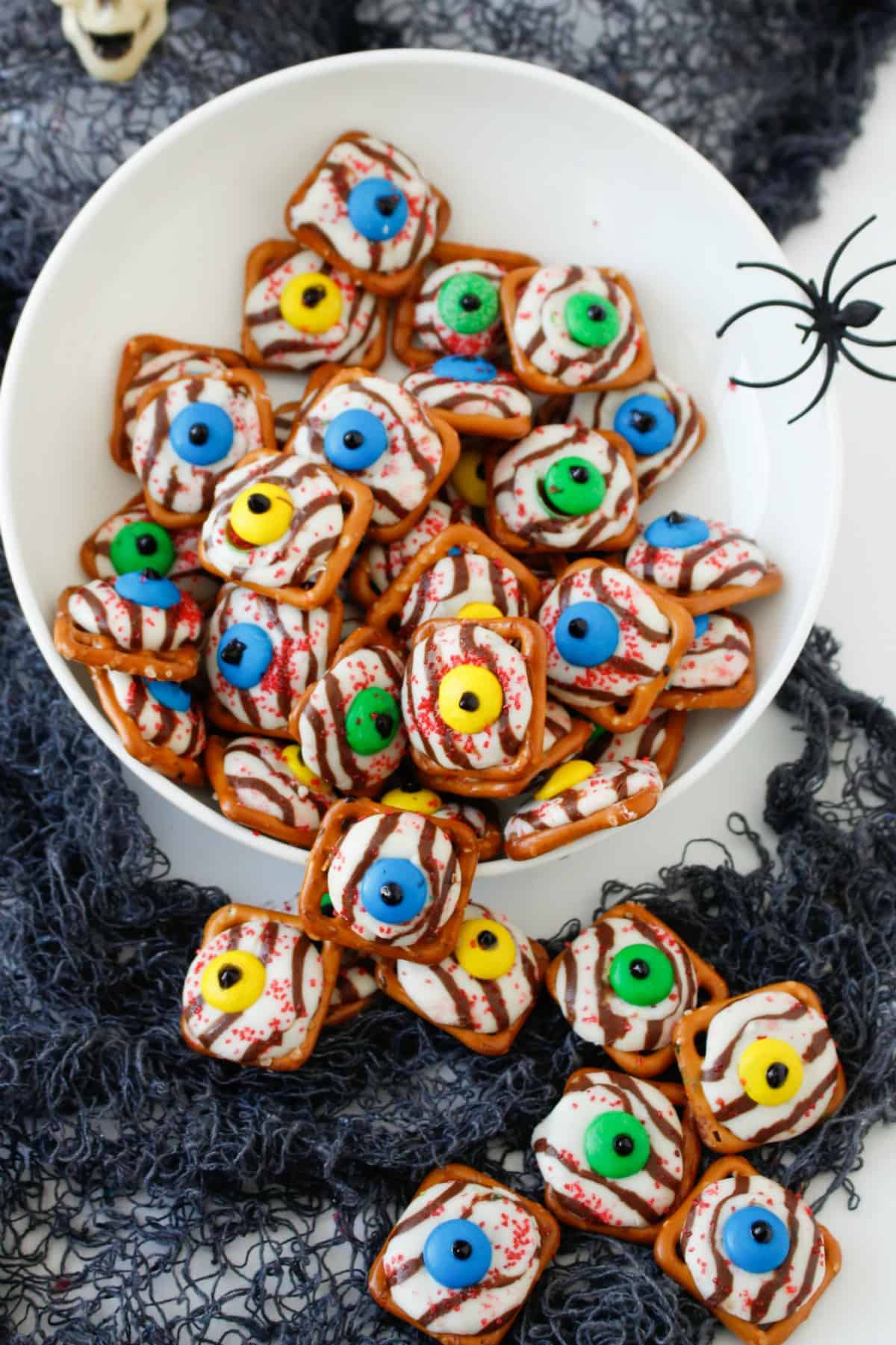 Halloween Pretzel Eyeballs in a white bowl with a spider