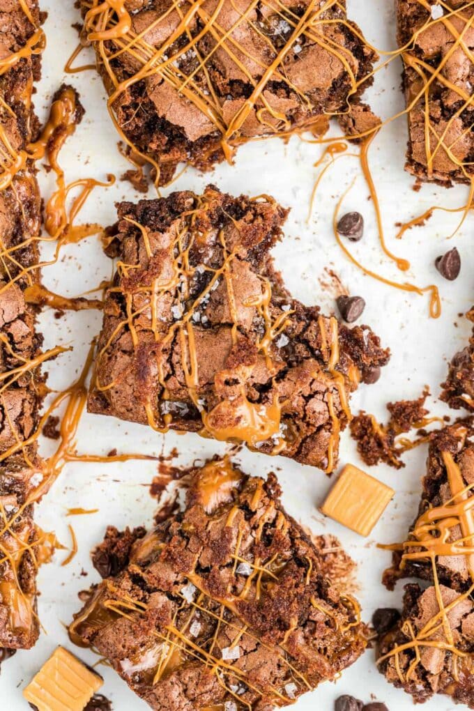 Salted Caramel Brownies on white background with caramel drizzle and a bite out of one