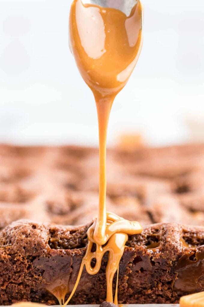 caramel dripping off a spoon on top of brownies