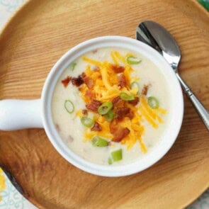 A bowl of loaded potato soup on a wooden plated