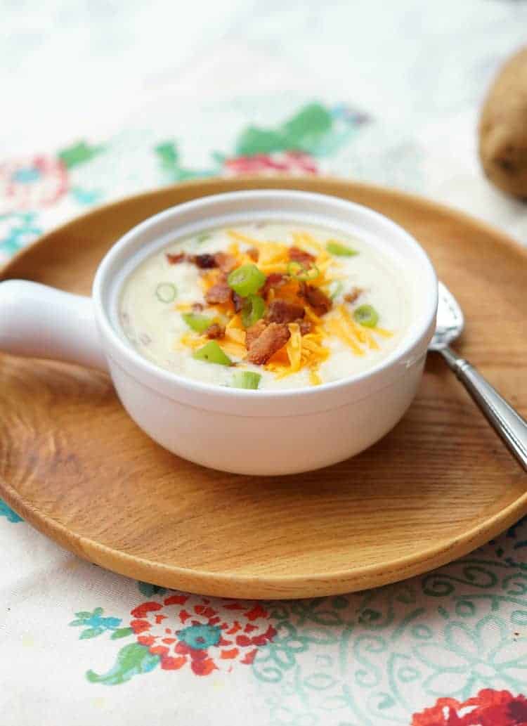 A bowl of loaded potato soup on a wooden plated