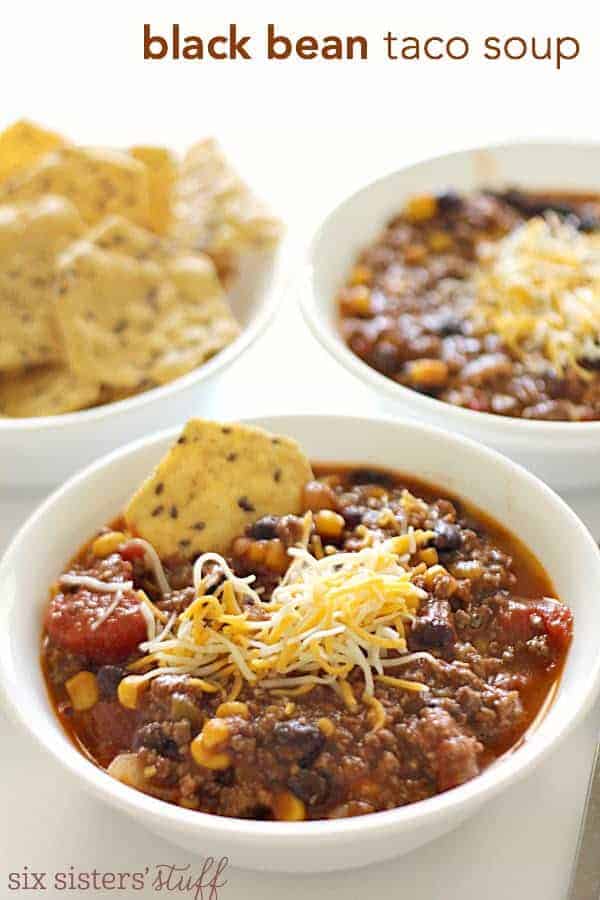 White bowls filled with black bean taco soup with chips and cheese on top