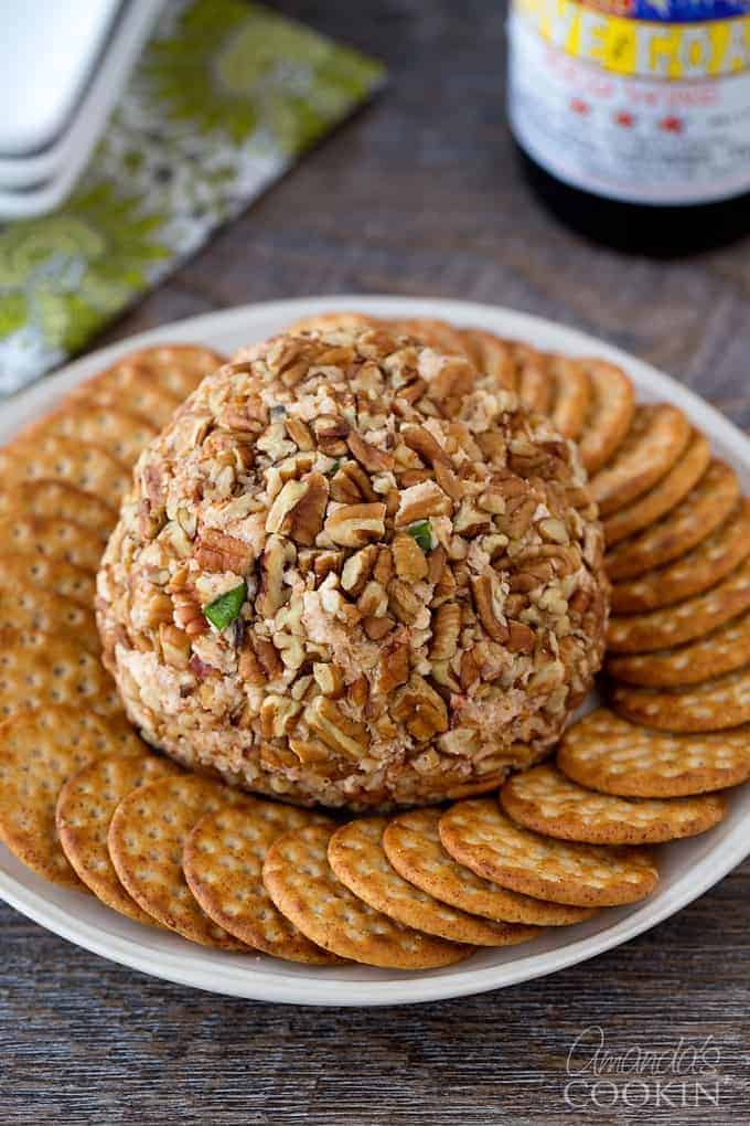 A cheese ball with crackers surrounding it on a white plate