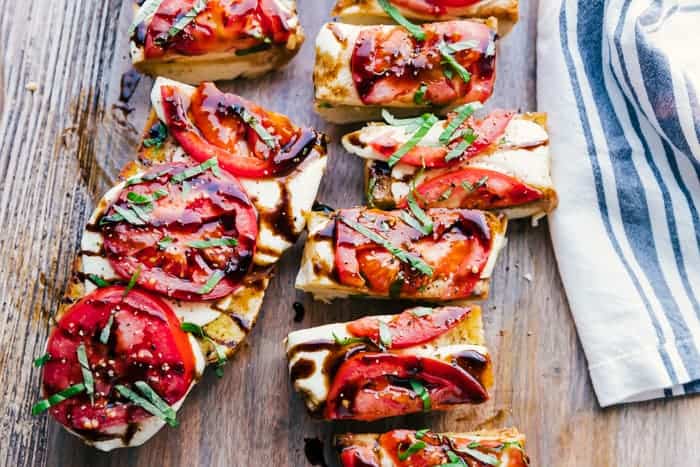 Caprese garlic bread topped with a balsamic glaze, sliced and served on a wooden serving platter-done in 15 minutes or less.