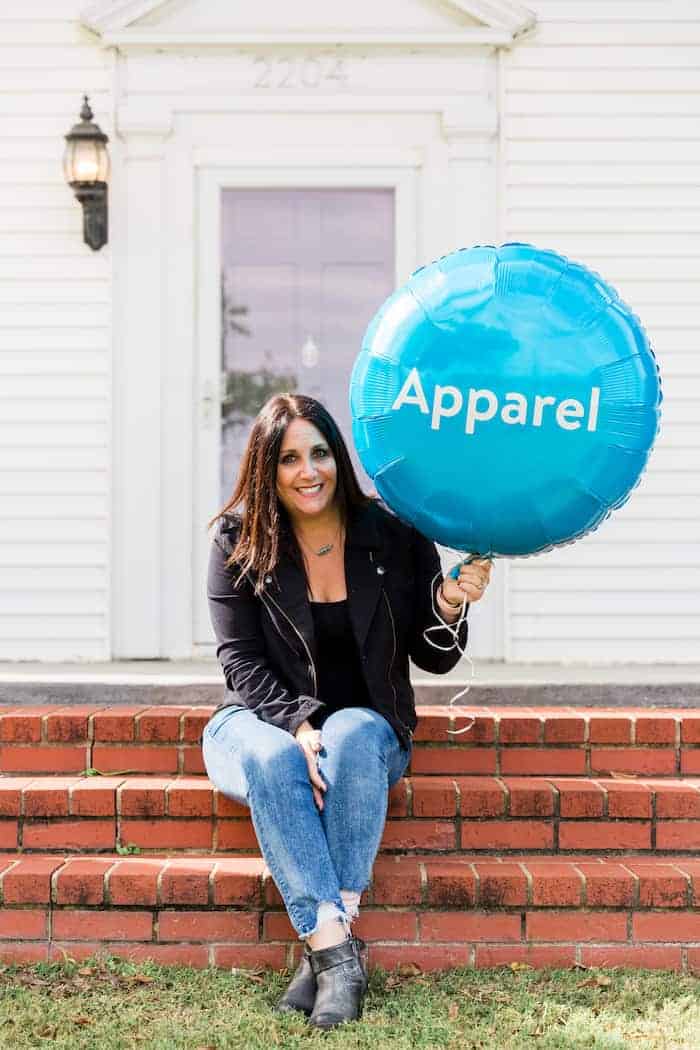 woman holding blue balloon with the word apparel on it