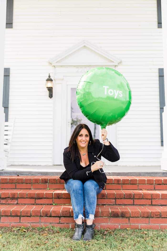 woman holding green balloon with the word toys on it