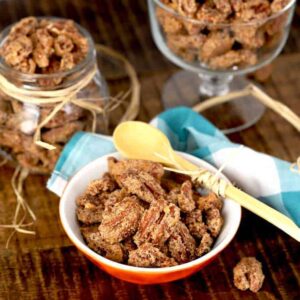 Candied Pecans in different containers on a wooden surface.